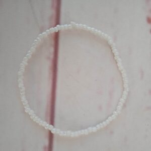 Armbånd med hvide akryl perler Omkreds på ca. 18 cm. Det er lavet på elastiksnor, så kan passe de fleste.