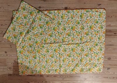 Baby sengetøj - med gule, orange og grønne blomster.